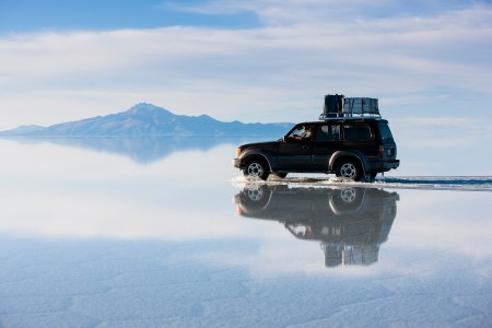 Traversing the ethereal expanse of the Salar de Uyuni, our trusty 4x4 stands as a solitary sentinel against the vast sea of salt, bridging the endless sky and earth in Bolivia’s surreal landscape.